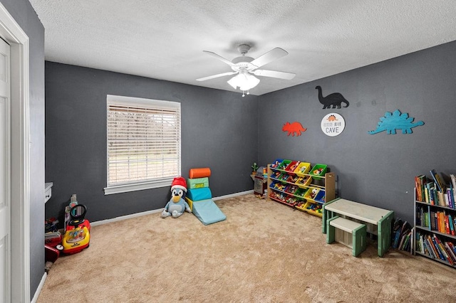 rec room with a ceiling fan, baseboards, a textured ceiling, and light colored carpet