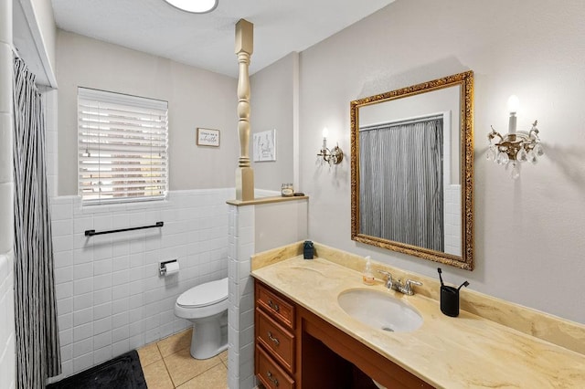 bathroom with wainscoting, toilet, tile patterned floors, vanity, and tile walls