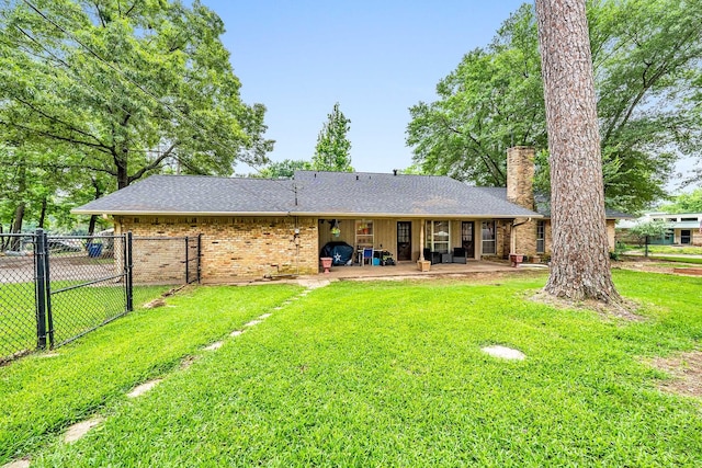 rear view of property featuring brick siding, a lawn, and a patio