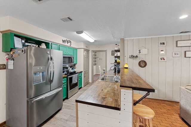 kitchen featuring visible vents, butcher block counters, appliances with stainless steel finishes, green cabinets, and a sink