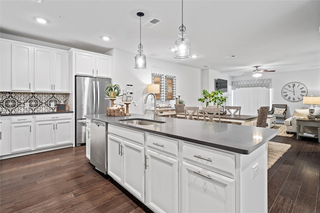 kitchen featuring dark countertops, a center island with sink, and a sink