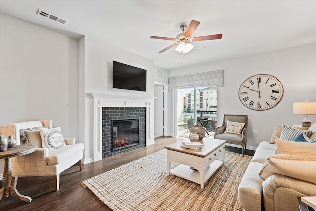 living area featuring baseboards, visible vents, a ceiling fan, wood finished floors, and a fireplace