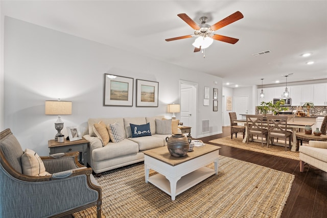 living room with ceiling fan, visible vents, dark wood-style flooring, and recessed lighting