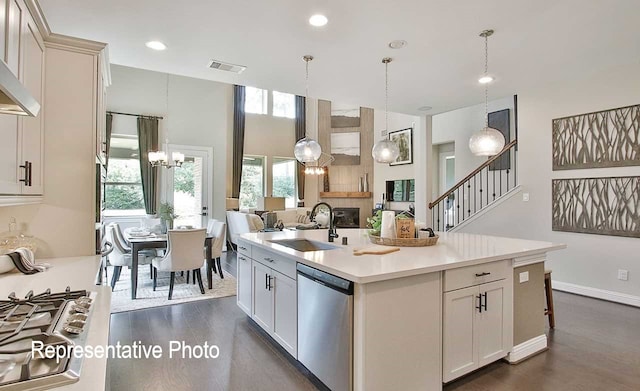 kitchen with a center island with sink, light countertops, visible vents, stainless steel dishwasher, and open floor plan