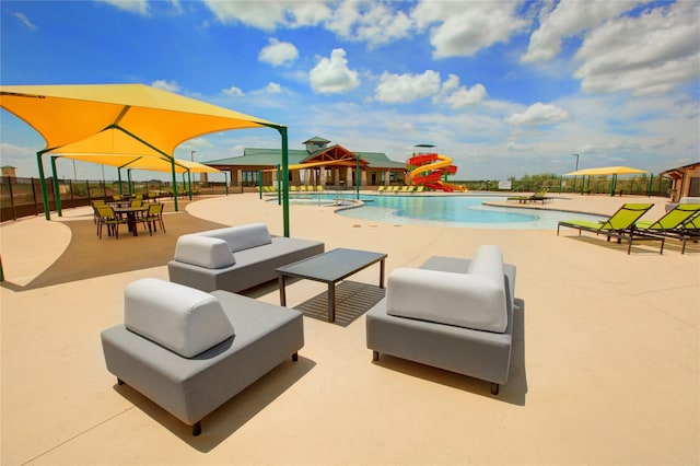 pool featuring outdoor lounge area, a water slide, a patio area, and fence