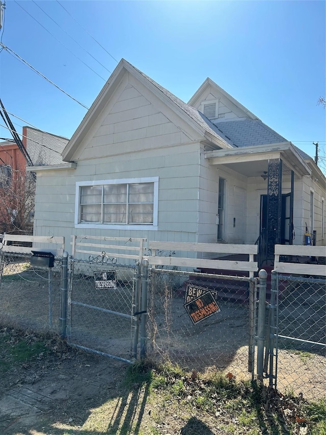 exterior space with a fenced front yard, cooling unit, a gate, and a shingled roof