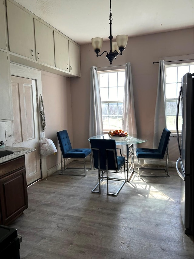 dining area with light wood-type flooring and an inviting chandelier