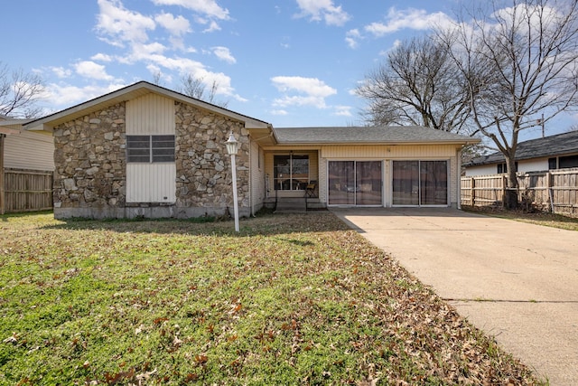 mid-century modern home with driveway, stone siding, an attached garage, fence, and a front lawn