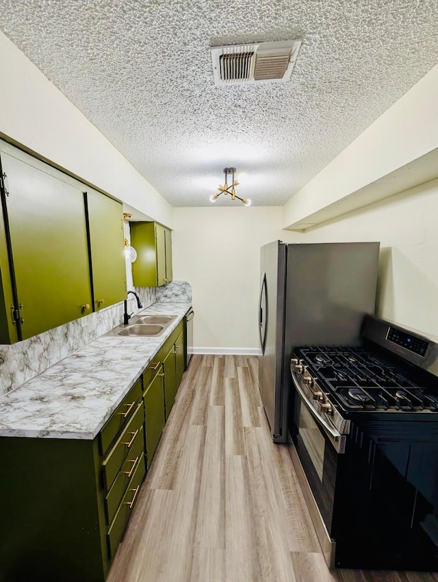 873 Beverly Dr, Terrell, TX 75160 - kitchen with green cabinets, stainless steel appliances, a sink, a textured ceiling, and light wood-type flooring