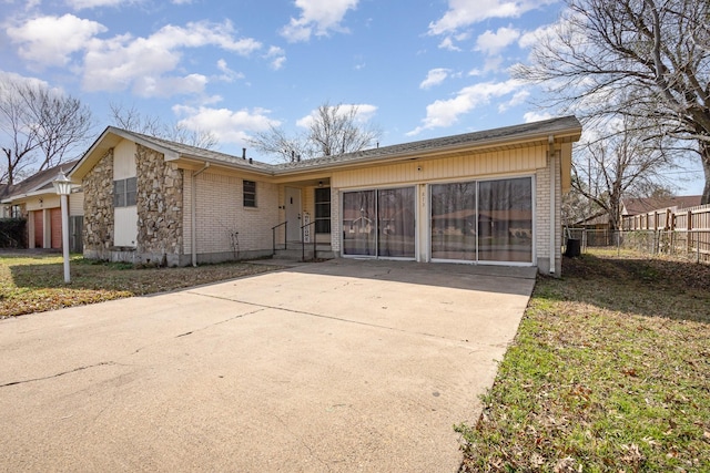 single story home featuring driveway, a garage, fence, a front lawn, and brick siding