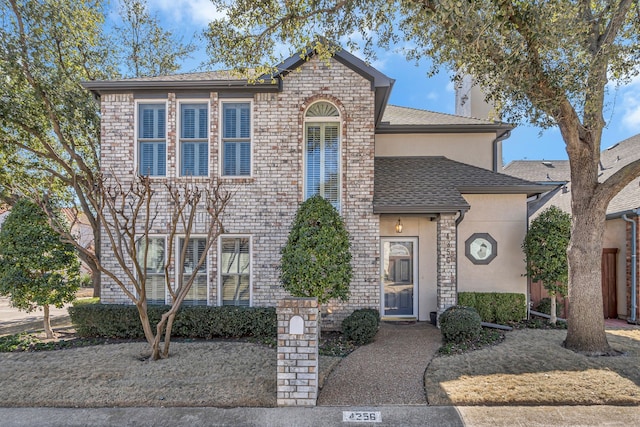 traditional-style home with roof with shingles and stucco siding