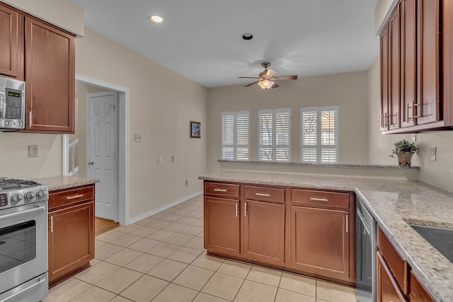 kitchen with a ceiling fan, brown cabinets, light stone countertops, stainless steel appliances, and light tile patterned flooring