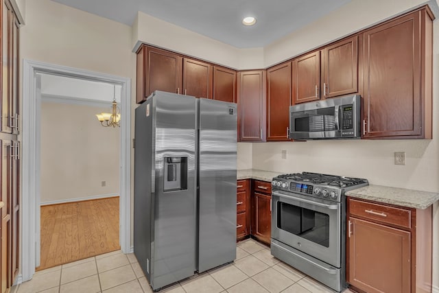 kitchen featuring light tile patterned floors, light stone counters, hanging light fixtures, an inviting chandelier, and stainless steel appliances