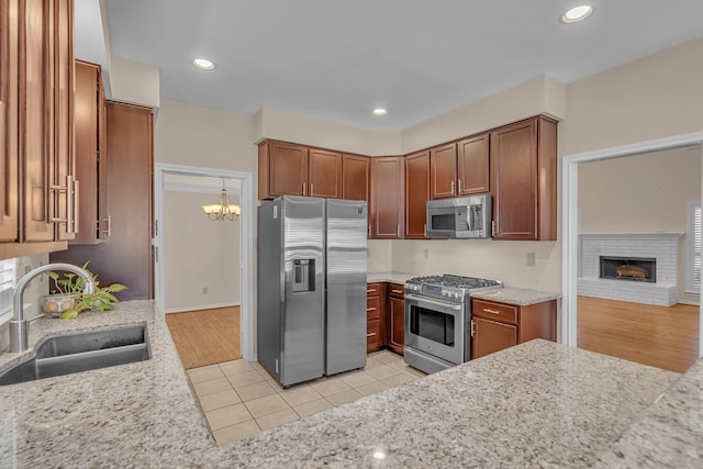 kitchen with light tile patterned floors, appliances with stainless steel finishes, a brick fireplace, a sink, and recessed lighting