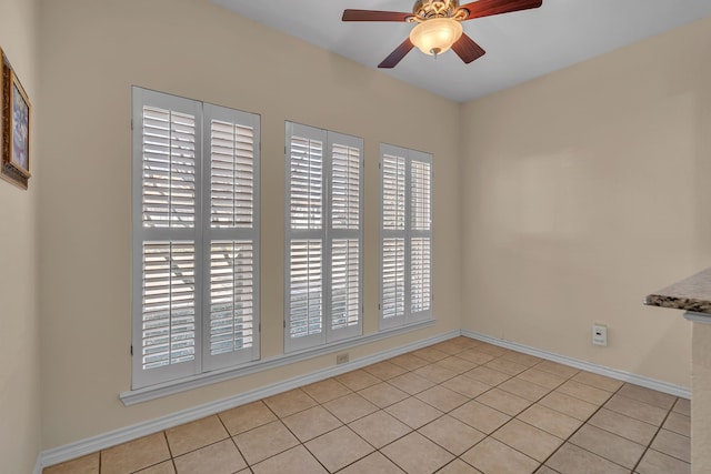 unfurnished room with ceiling fan, light tile patterned floors, and baseboards