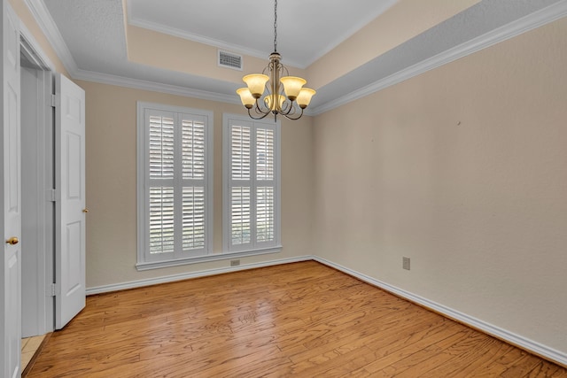 interior space with light wood-type flooring, crown molding, a tray ceiling, and a notable chandelier