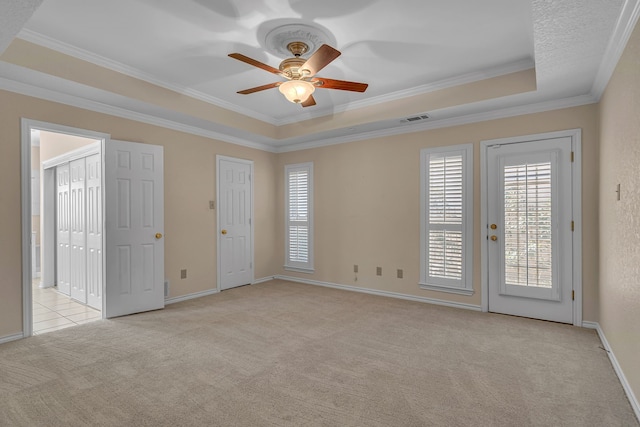 interior space with ornamental molding, a raised ceiling, visible vents, and light carpet