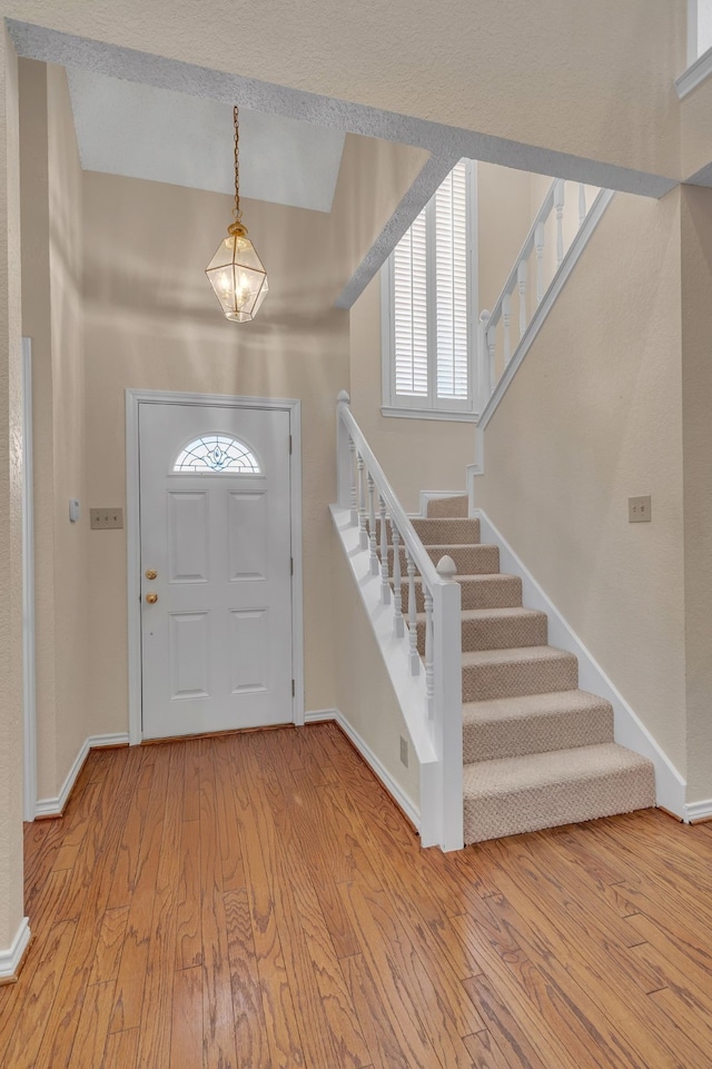 entryway with light wood finished floors, stairs, and baseboards