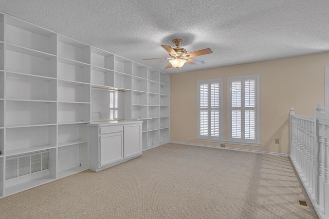 spare room featuring a textured ceiling, baseboards, visible vents, and light colored carpet