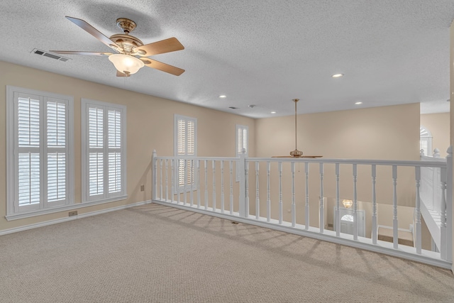 carpeted spare room featuring baseboards, visible vents, a textured ceiling, and recessed lighting