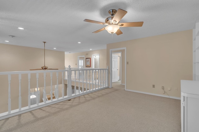 spare room with recessed lighting, light carpet, a textured ceiling, and baseboards