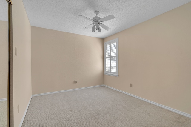 unfurnished room featuring baseboards, a textured ceiling, a ceiling fan, and light colored carpet