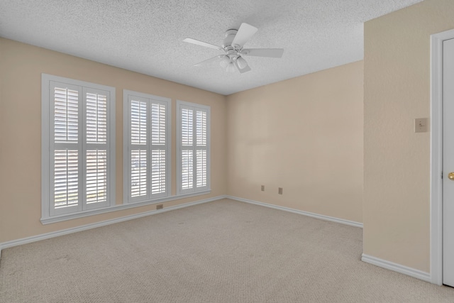 spare room featuring a ceiling fan, light colored carpet, a textured ceiling, and baseboards