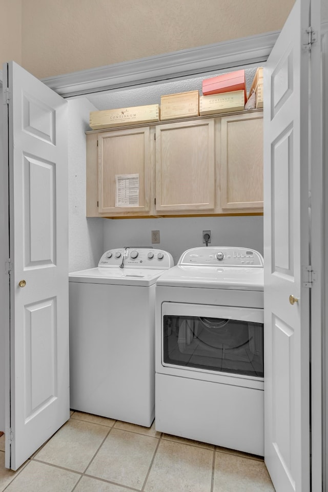 laundry area with light tile patterned floors, washing machine and clothes dryer, and cabinet space