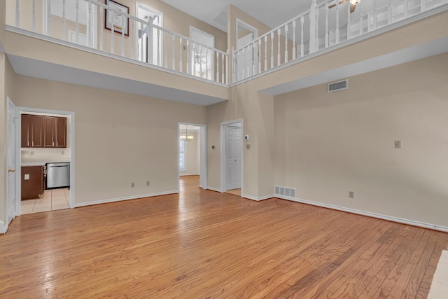 unfurnished living room with light wood-type flooring, visible vents, and baseboards