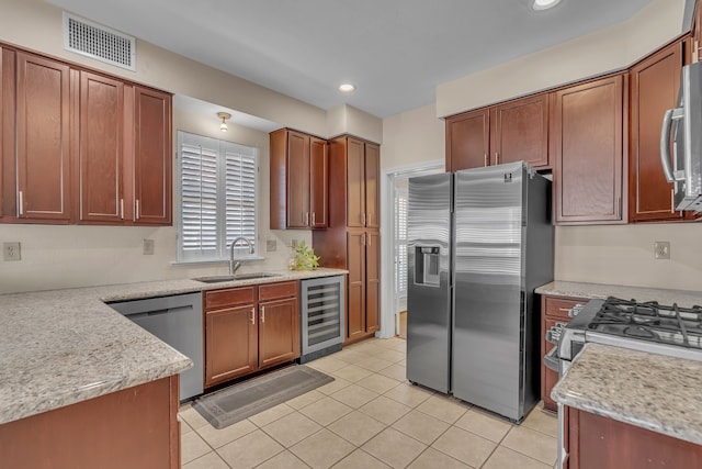 kitchen featuring wine cooler, visible vents, appliances with stainless steel finishes, a sink, and light stone countertops