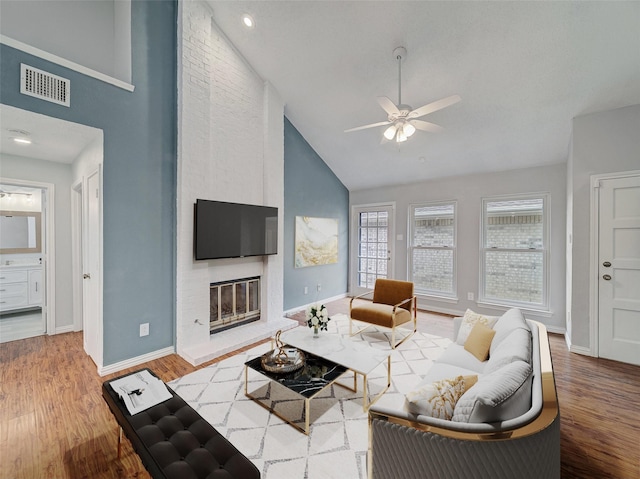 living room with visible vents, a fireplace, baseboards, and wood finished floors