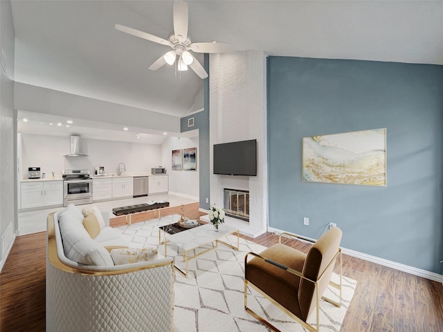 living room with baseboards, light wood-style floors, a ceiling fan, and vaulted ceiling