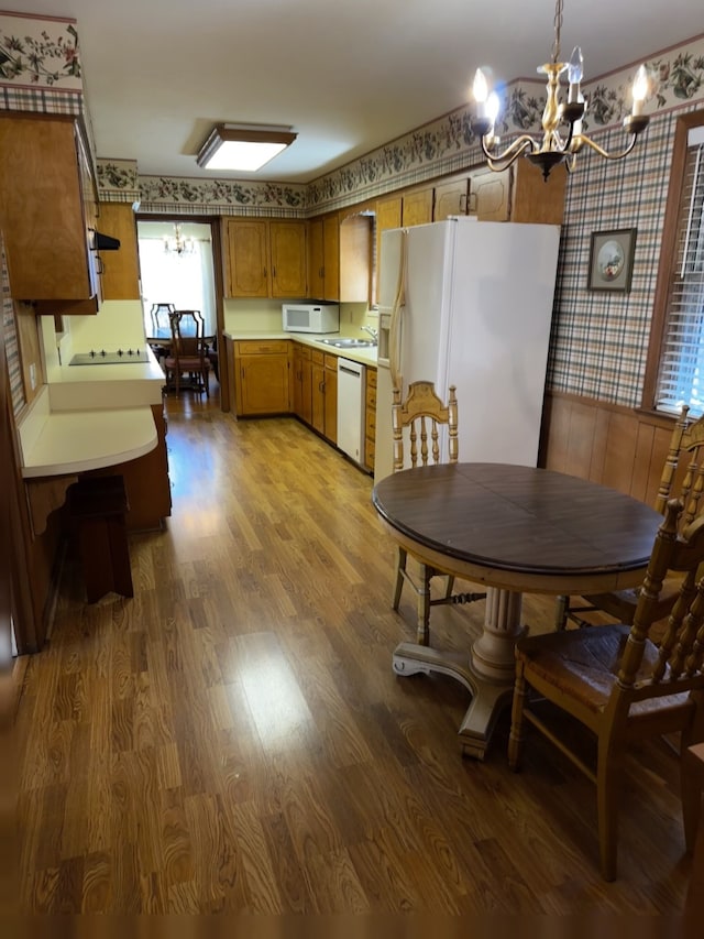 kitchen featuring a chandelier, white appliances, light countertops, and hanging light fixtures