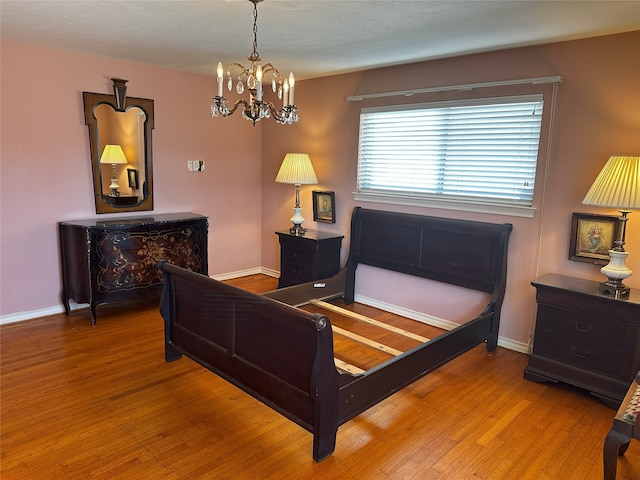 bedroom with an inviting chandelier, baseboards, and wood finished floors