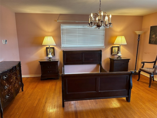 bedroom with baseboards, a notable chandelier, and light wood finished floors