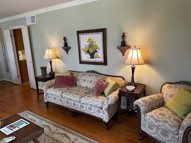 living area featuring baseboards, wood finished floors, visible vents, and crown molding