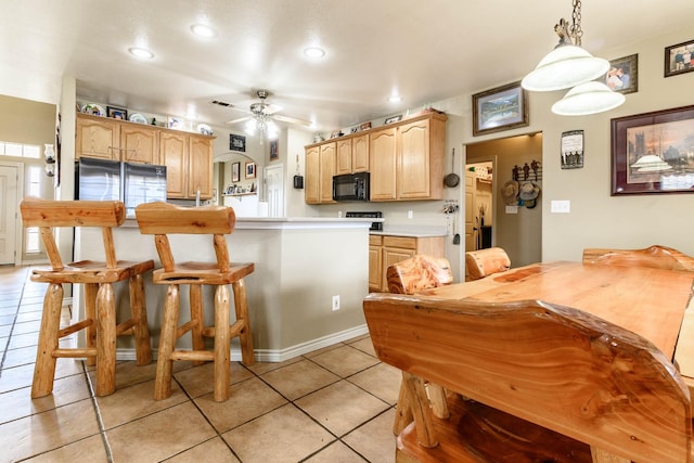 kitchen featuring light tile patterned floors, light countertops, light brown cabinetry, black microwave, and pendant lighting