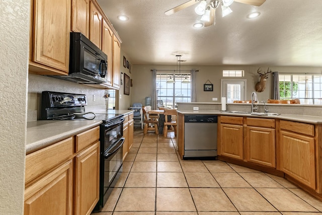 kitchen with light countertops, hanging light fixtures, a sink, plenty of natural light, and black appliances