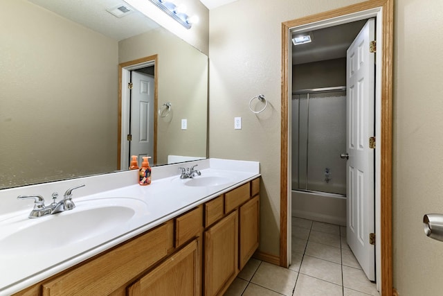 bathroom featuring tile patterned floors, visible vents, a sink, and bath / shower combo with glass door