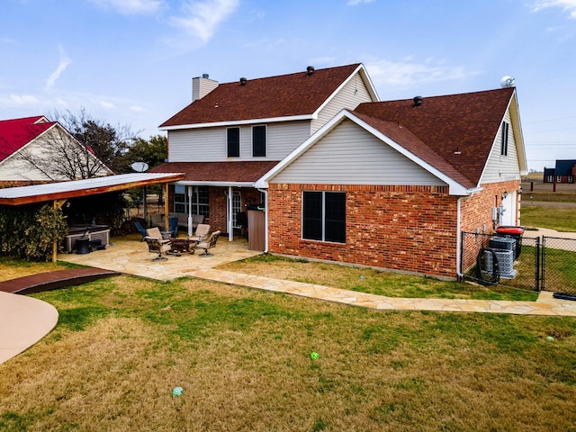 rear view of house featuring an outdoor fire pit, a lawn, a patio, a chimney, and brick siding