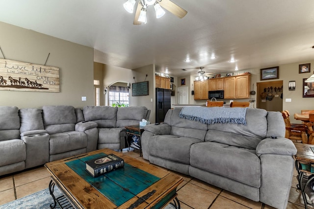 living room with arched walkways, a ceiling fan, and light tile patterned flooring