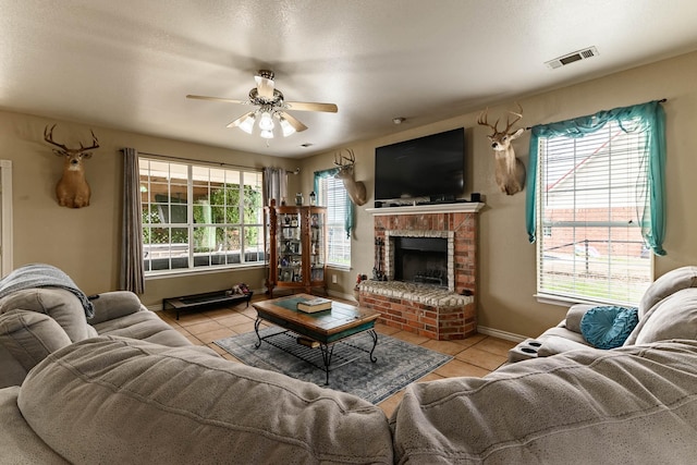 living room with light tile patterned flooring, a fireplace, visible vents, and a ceiling fan