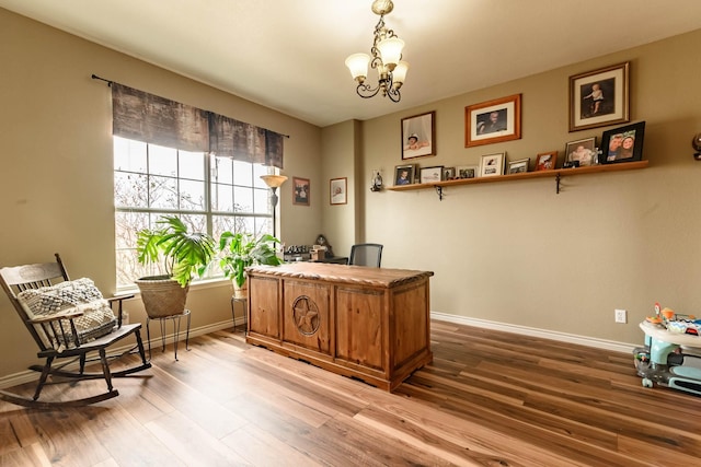 office space with an inviting chandelier, baseboards, and wood finished floors