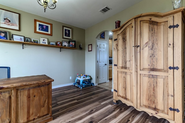 interior space with dark wood-style floors, arched walkways, visible vents, and baseboards