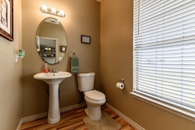 bathroom with wood finished floors, toilet, and baseboards