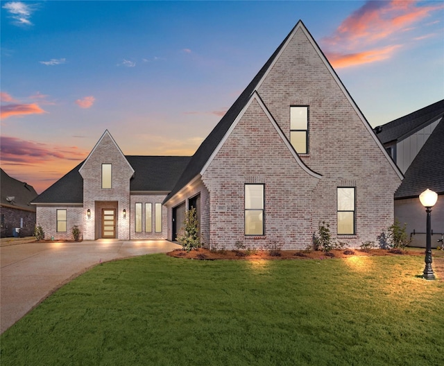 view of front facade featuring concrete driveway, brick siding, and a lawn