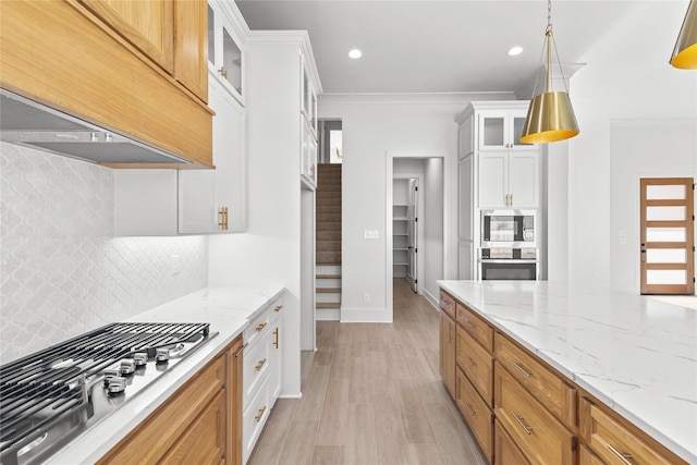 kitchen featuring decorative light fixtures, stainless steel appliances, glass insert cabinets, white cabinets, and premium range hood