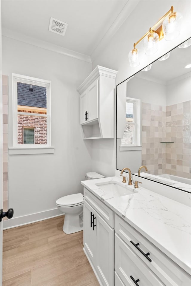 full bath featuring visible vents, ornamental molding, vanity, wood finished floors, and baseboards