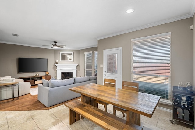 living area with visible vents, a fireplace, ornamental molding, and a ceiling fan