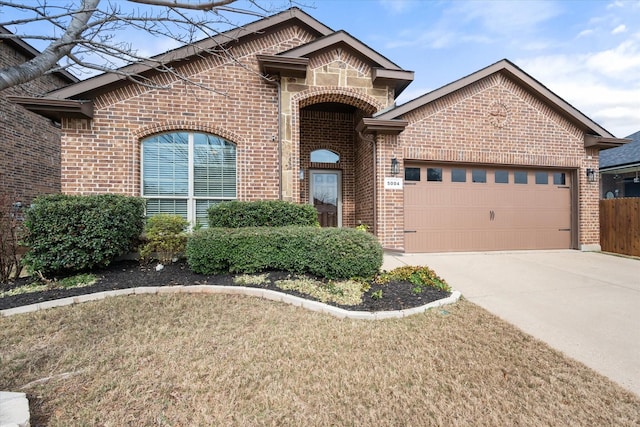 view of front of house featuring brick siding, a garage, stone siding, driveway, and a front lawn